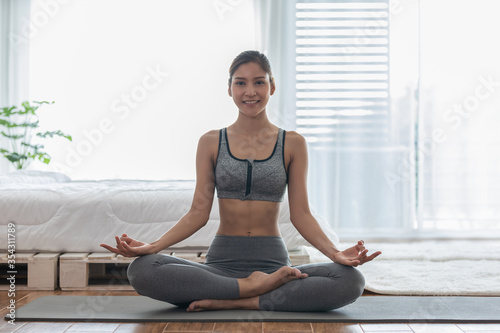 Attractive Asian woman practice yoga lotus pose to meditation in bedroom after wake up in the morning Feeling so comfortable and relax at home,Health care and Exercise at home Concept