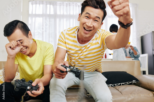 Excited young Vietnamese man celebrating his victory in video game