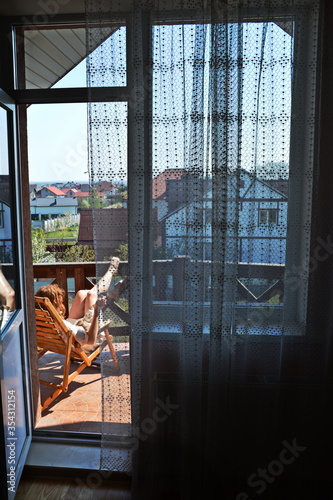 red-haired girl resting on the balcony in a bathrobe and drinking coffee  overlooking the city in the morning 