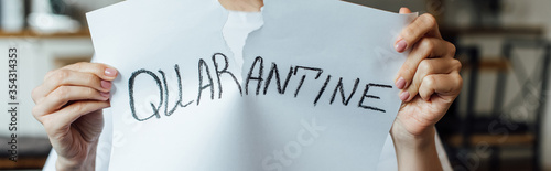 Cropped view of woman tearing card with quarantine lettering  panoramic crop