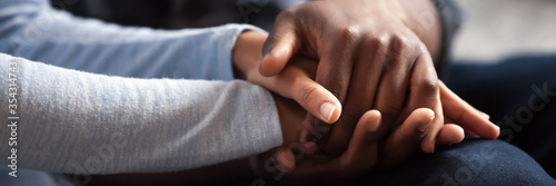 Close up photo african couple in love, woman man holding hands. Gesture of sincere feelings, compassion, apology, reliable friend, share pain or happiness. Horizontal banner for website header design photo