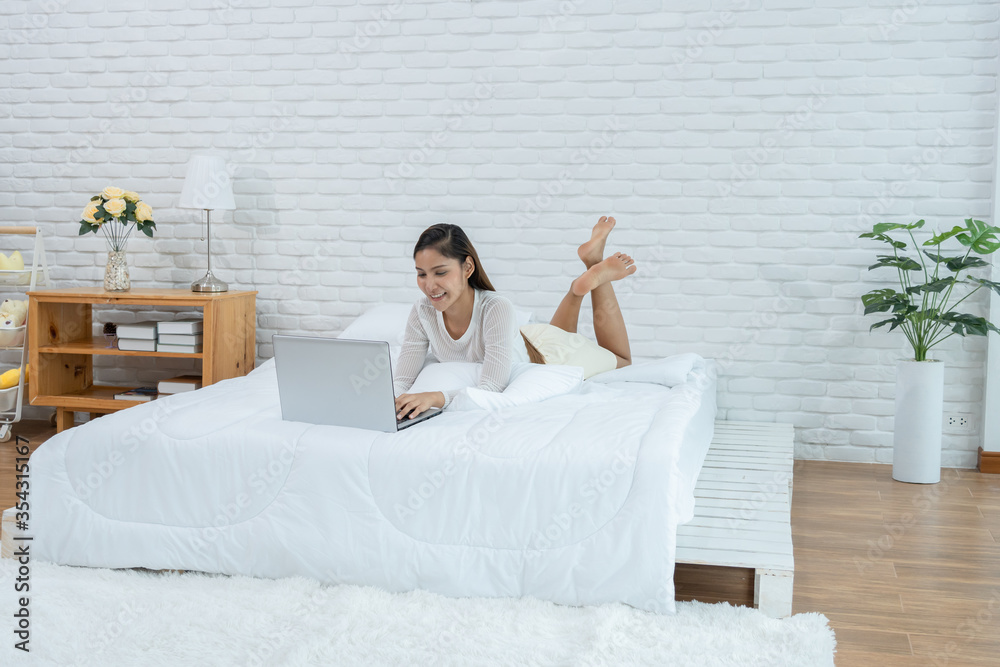 Asian young woman on bed using computer laptop for shopping online Asian young woman on bed using computer laptop for shopping online