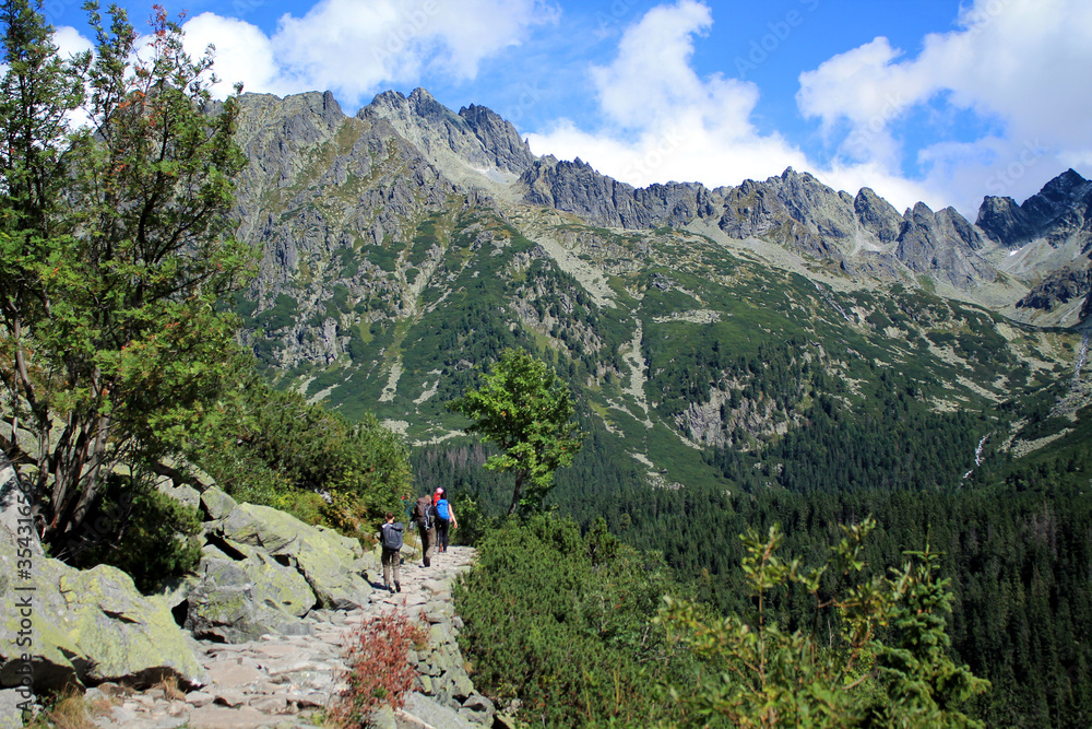 Hikers climb a stone trail up to the top of mountain in High Tatras .