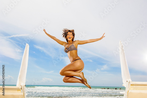 Ragazza in bikini salta sulla spiaggia