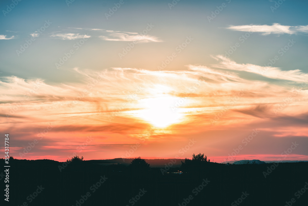 A deep red sunset in the silhouette of mountains and trees A deep red sunset in the silhouette of mountains and trees
