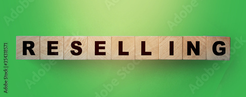Resselling word wooden cubes on the green background. Business model concept photo