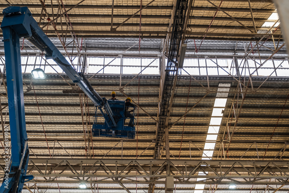 Technician use boom lift Install Electrical system. In the industrial plant, pipe assembly, red fire pipe, fire protection contractors Using Scissor Lift High work