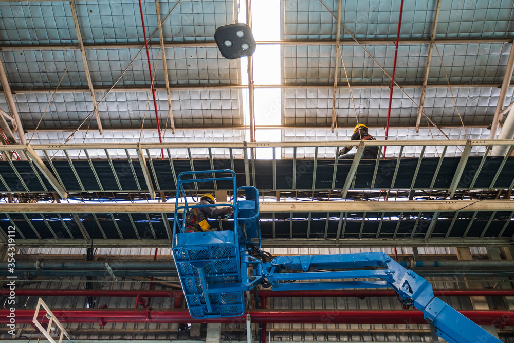Technician use boom lift Install Electrical system. In the industrial plant, pipe assembly, red fire pipe, fire protection contractors Using Scissor Lift High work