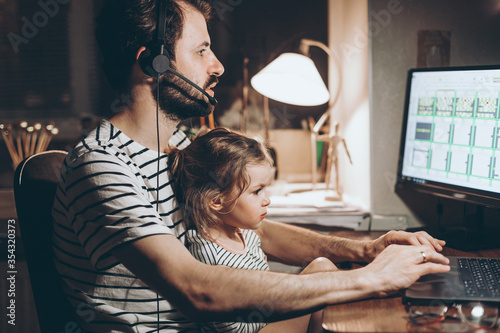 Father and daughter are working on a laptop. businessman working from home and watching the child. A young man works on a computer. Launch. Freelancer concept. Family on quarantine photo