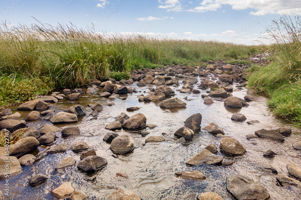 Obraz premium Shallow river Daliyot flowing near the remnants of the early Bronze Age megalithic complex of the early Bronze Age - Wheels of Spirits - Rujum Al-Hiri - Gilgal Rephaeem - on Golan Heights in Israel