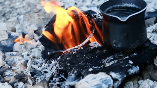 Placing coffee pot on top of small campfire with a rocky terrain in slow motion