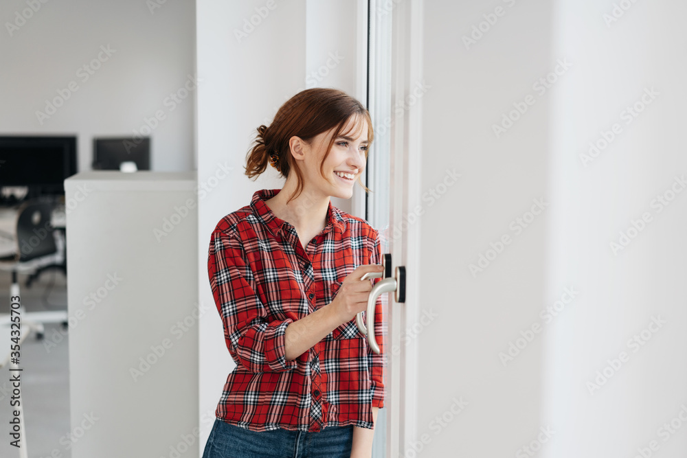 Woman smiling as she watches through a glass door