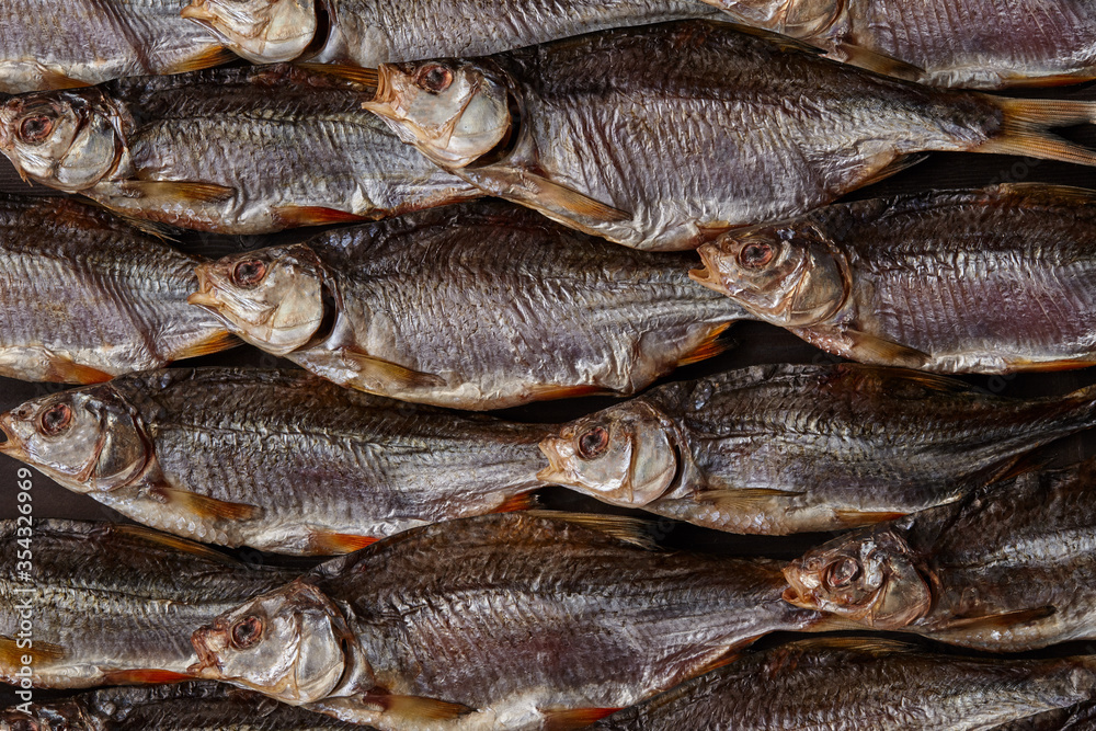 Lots of dried or jerky salted taranka. Fishes background. Salty beer appetizer. Traditional way of preserving fish. Close up Lots of dried or jerky salted taranka. Fishes background. Salty beer appetizer. Traditional way of preserving fish. Close up