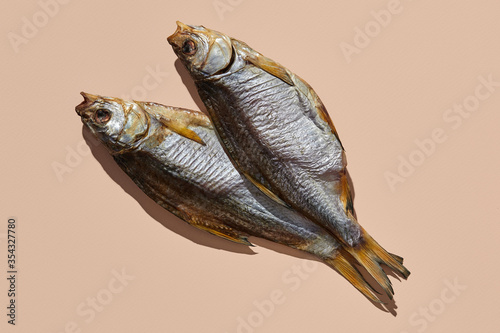 Two dried or jerky salty taranka, yummy clipfish on pink background. Popular beer appetizer. Traditional way of preserving fish. Close up photo