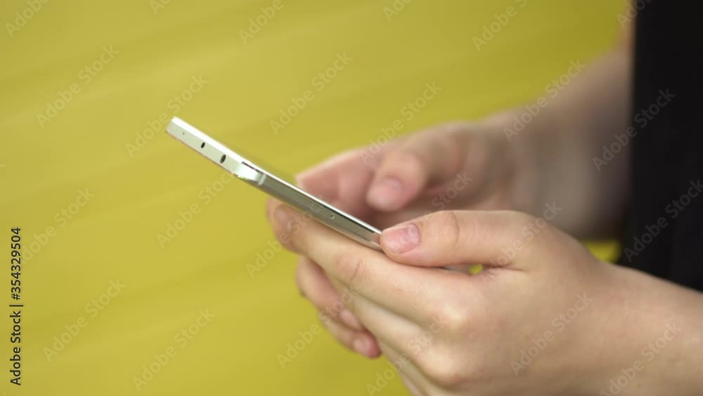Side view. Hand of girl using smartphone, typing message. Close-up of young women hands Side view. Hand of girl using smartphone, typing message. Close-up of young women hands