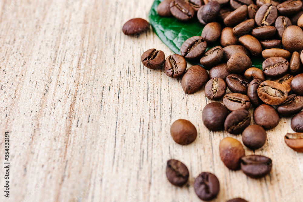 Coffee beans scattered on a light wooden table, top view, closeup grains, place to insert text, copy space Coffee beans scattered on a light wooden table, top view, closeup grains, place to insert text, copy space
