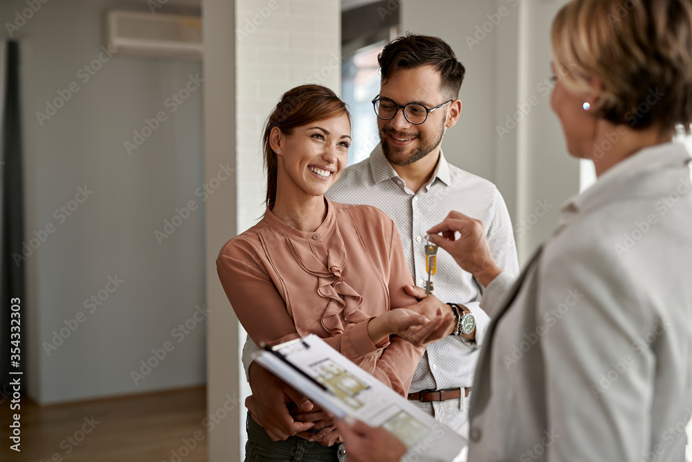 Young happy couple receiving keys of their new home from real estate agent. Young happy couple receiving keys of their new home from real estate agent.