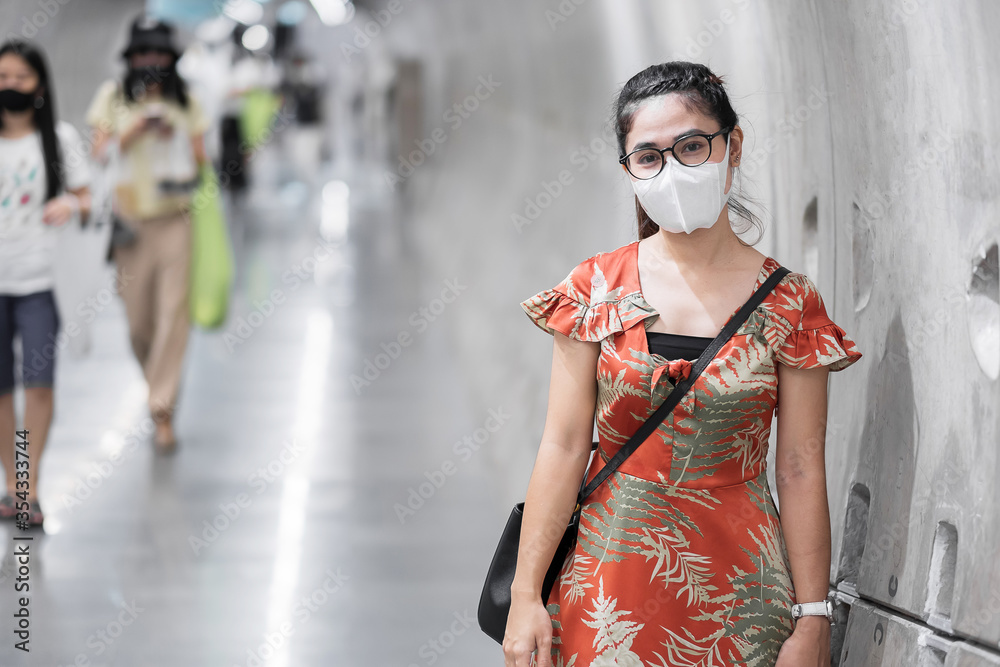 young Asian girl wearing Surgical face mask protect coronavirus inflection, Happy tourist woman  walking in public subway station. social distancing, new normal and life after covid-19 pandemic