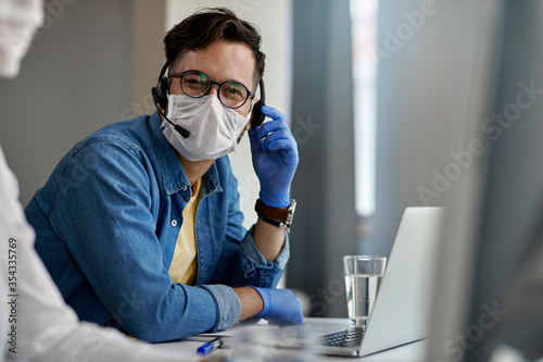 Happy call senter agent wearing protective face mask while working during coronavirus epidemic. photo