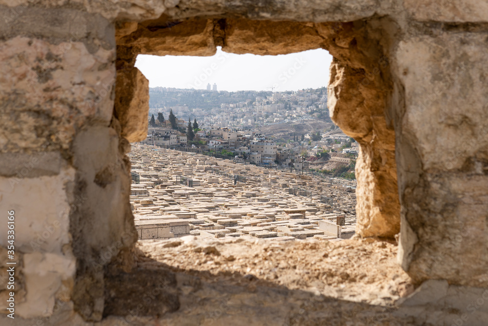 View of jewish cemetery on Mount of Olives in Jerusalem through a hole in the wall