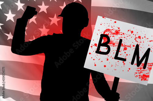 Black Lives Matter. Man holds a poster with the inscription BLM. Black protests in USA. Protester on background of flag of America. Protestor’s transparency is stained with blood. Against police USA photo