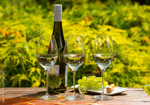 Quality wine tasting on winery in Mosel wine redion in Germany, three glasses and one bottle of riesling white wine served outdoor in sunny day