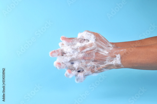Washing hands with soap on blue background. Closeup of person washing hands. Cleaning Hands. Cleanliness and body care concept.