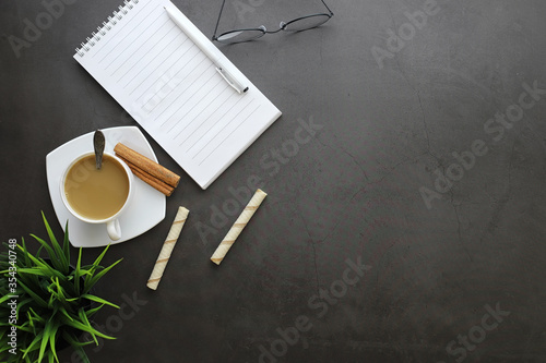 Office desktop background with a cup of coffee and writing utensils. Manager's desk, pen, notebook, computer.