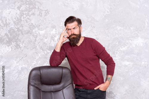 Dressing smart and fashionable. Fashionable look of bearded man. Serious hipster stand at office chair. Fashionable manager wear casual style. Fashionable outfit. Fashion and style. Mens wardrobe