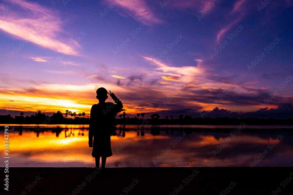 Amazing sunset and sunrise.Dark tree on open field dramatic sunrise.Panorama.Countryside Landscape Under Scenic Colorful Sky At Sunset Dawn.With the silhouette of the boy.