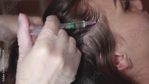 The doctor makes injections into the scalp for hair growth. Mesotherapy for hair growth and strengthening in the beauty salon. Procedure against hair loss. Close-up, selective focus.