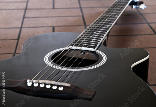Black acoustic guitar on the brick floor. Closeup top-down photo.