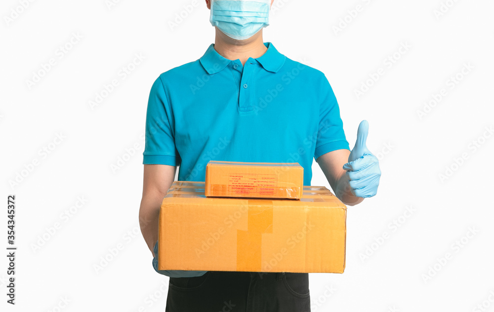 Delivery man employee in blue shirt uniform face mask gloves hold empty cardboard box isolated white background. Delivery man employee in blue shirt uniform face mask gloves hold empty cardboard box isolated white background.