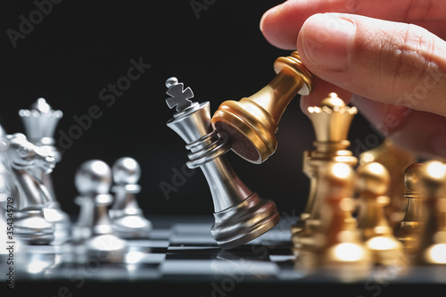 Hand of man moving gold chess battle figure in competition success play.
