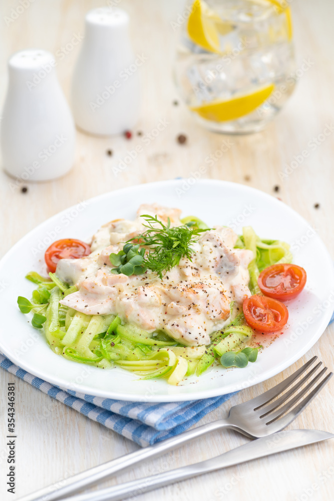 Salmon slices in creamy sauces and zucchini. Ketogenic food.