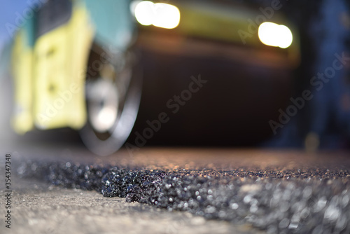 Road repair, thin layer of new asphalt close-up and road roller