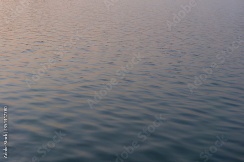 Water ripple surface reflection effect from sunset and sky top view at lake in evening day,wave abstract texture sunlight blue and golden pattern background