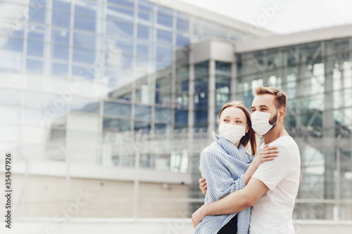 Happy man and woman in protective masks after coronavirus quarantine watch the landing of aircraft. Young couple near airport, opening air travel, travel concept