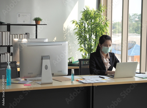 Asian business woman is wearing mask for protection from coronvirus or covid-19 or pm 2.5.Woman with flu working in the office.