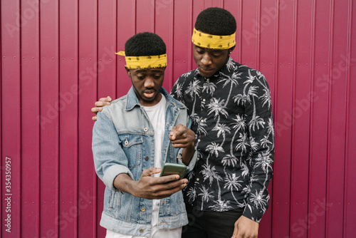 Portrait of two friends with headbands looking at cell phone