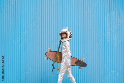 Kid dressed as an astronaut with longboard photo