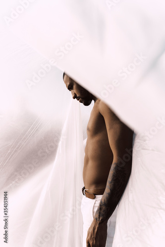 Barechested young man inside a plastic foil