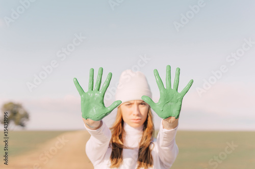 Young woman showing green painted palms photo