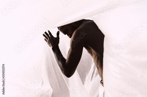 Barechested young man inside a plastic foil