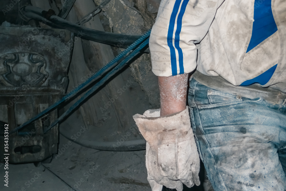 Gloved miner pulling a stone wagon with rope in a tunnel Gloved miner pulling a stone wagon with rope in a tunnel