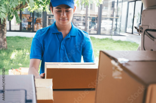 Delivery man loading cardboard boxes in a delivery van © ijeab