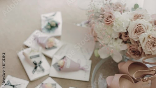 Small Armenian wedding gifts, bonbonniere or candy box presents. Set of wedding decorations. Beautiful bouquet of white roses. Mini bouquets of flowers, pink shoes in a glass case.