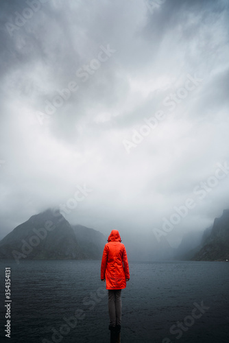 Rear view of man standing on coast against cloudy sky