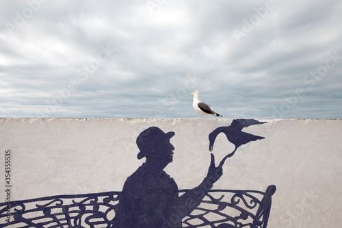 Morocco, Essaouira, wall painting of man wearing a bowler hat with seagull photo