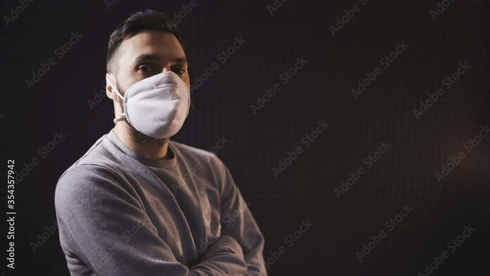 Side Profile of a young man wearing white face mask for protection and prevention. Isolated on black background Side Profile of a young man wearing white face mask for protection and prevention. Isolated on black background
